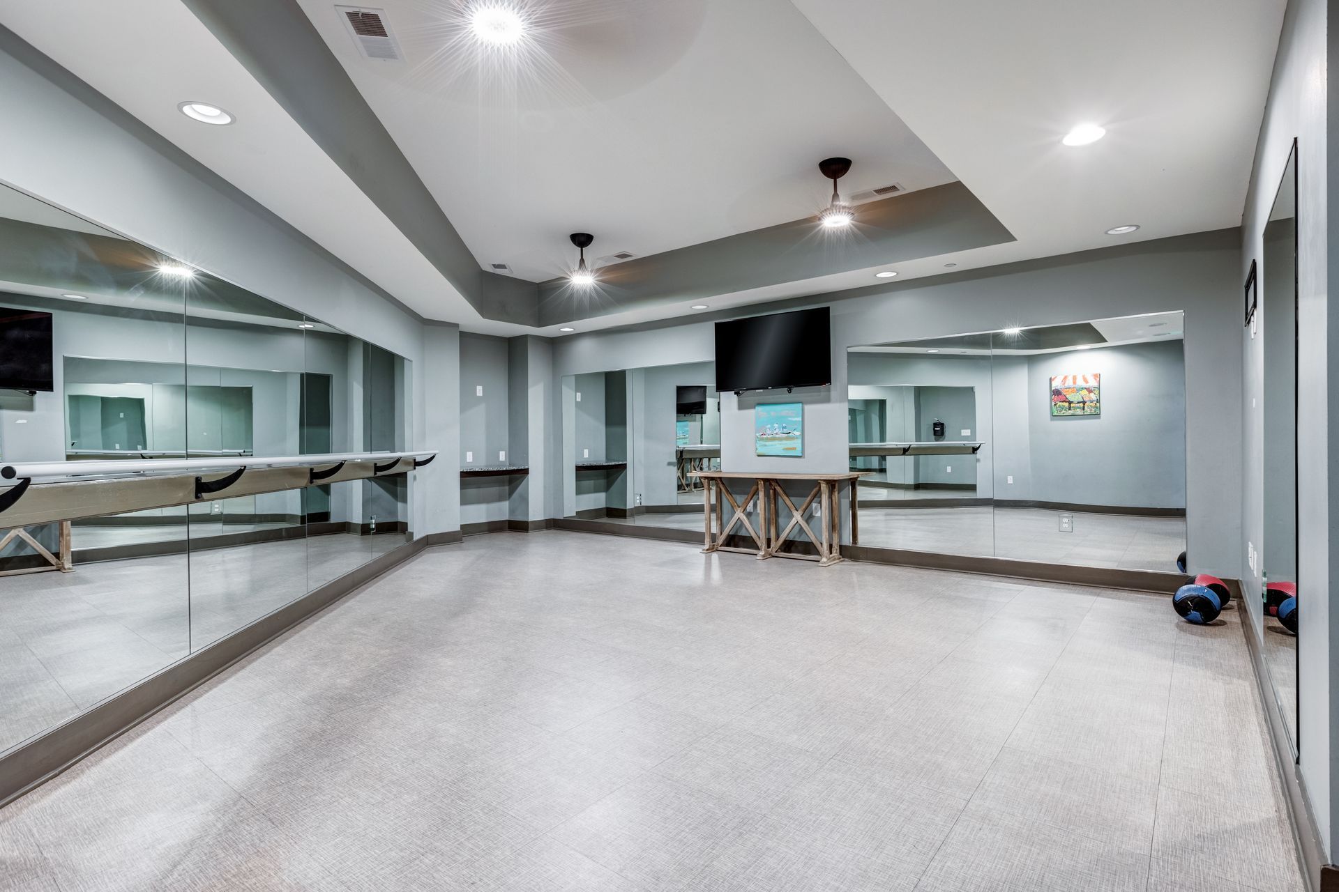 Dance studio with mirrors, grey walls, and a glossy floor. Ceiling lights and two fans are visible at Town Center at Lake Carolina in Columbia, SC.