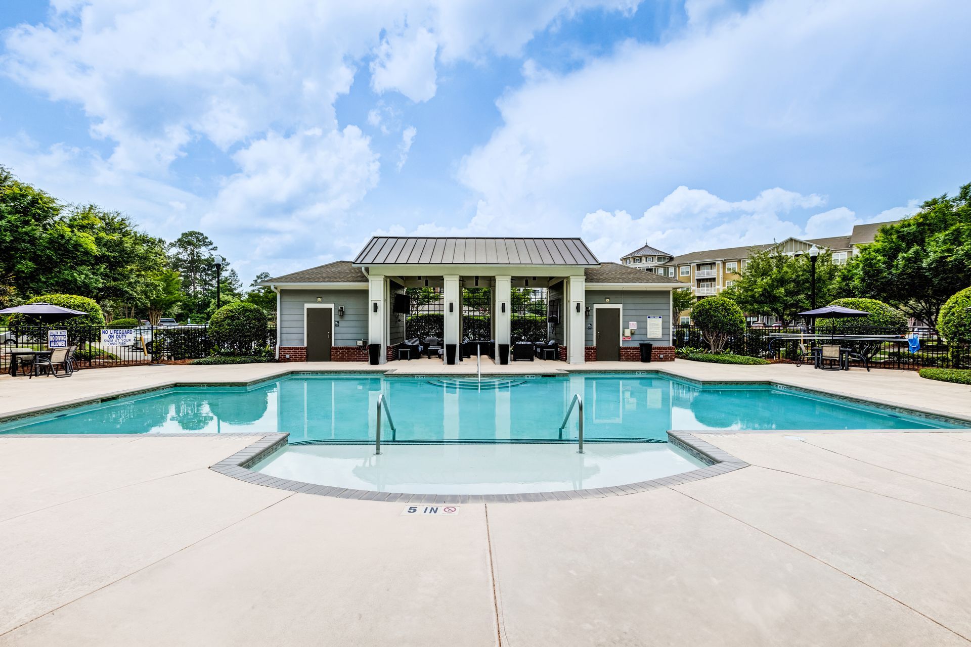 Swimming pool with a pavilion on a sunny day. Light blue water, gray building, and blue sky at Town Center at Lake Carolina in Columbia, SC.