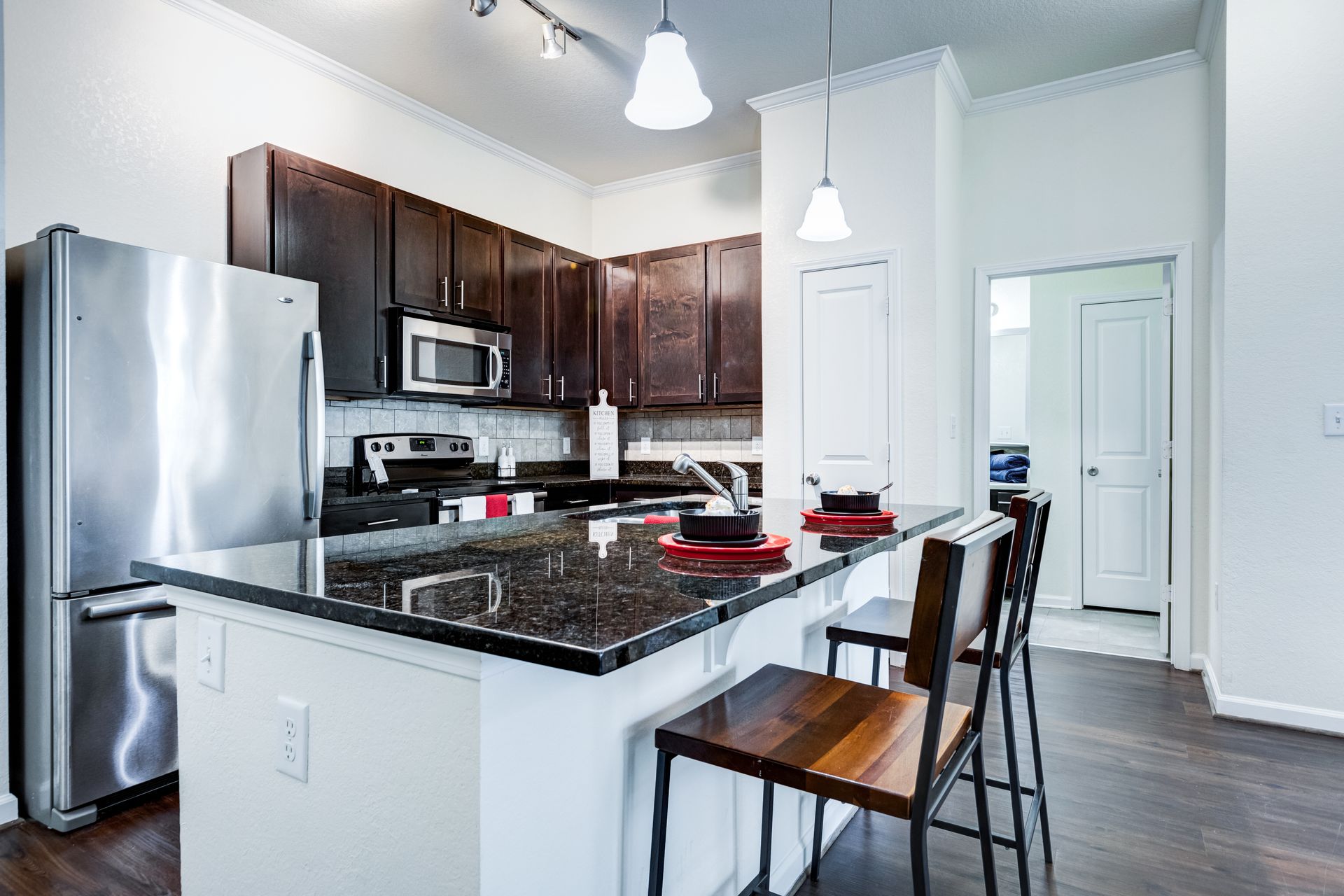 Modern kitchen with stainless steel appliances, dark cabinets, granite countertops, and bar seating at Town Center at Lake Carolina in Columbia, SC.