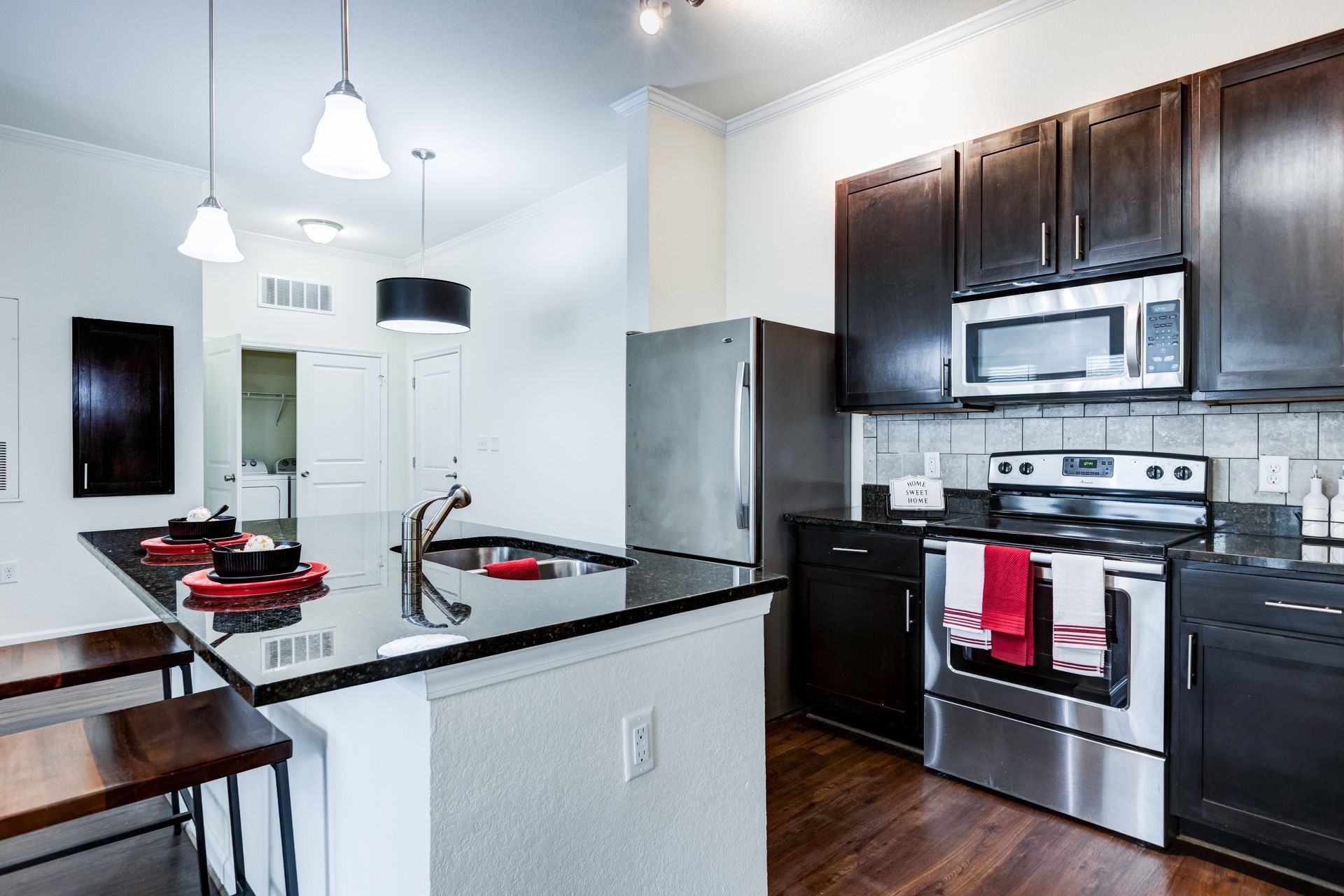 Modern kitchen with dark cabinets, stainless steel appliances, and a black countertop island with stools at Town Center at Lake Carolina in Columbia, SC.