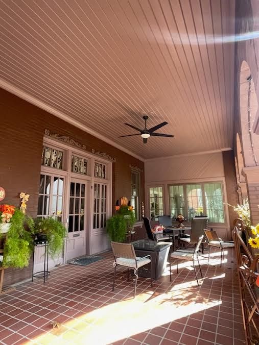 There is a ceiling fan on the porch of a house.