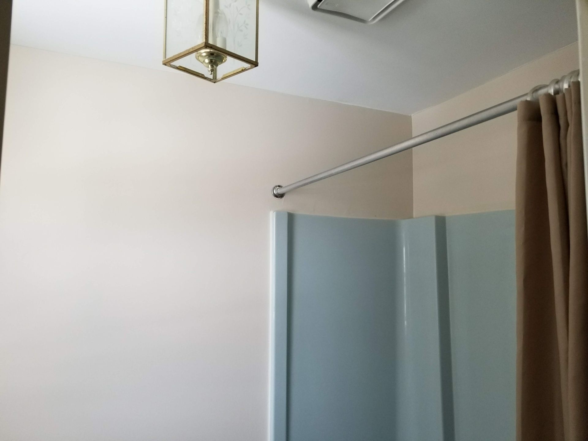 A bathroom with a shower curtain and a light hanging from the ceiling