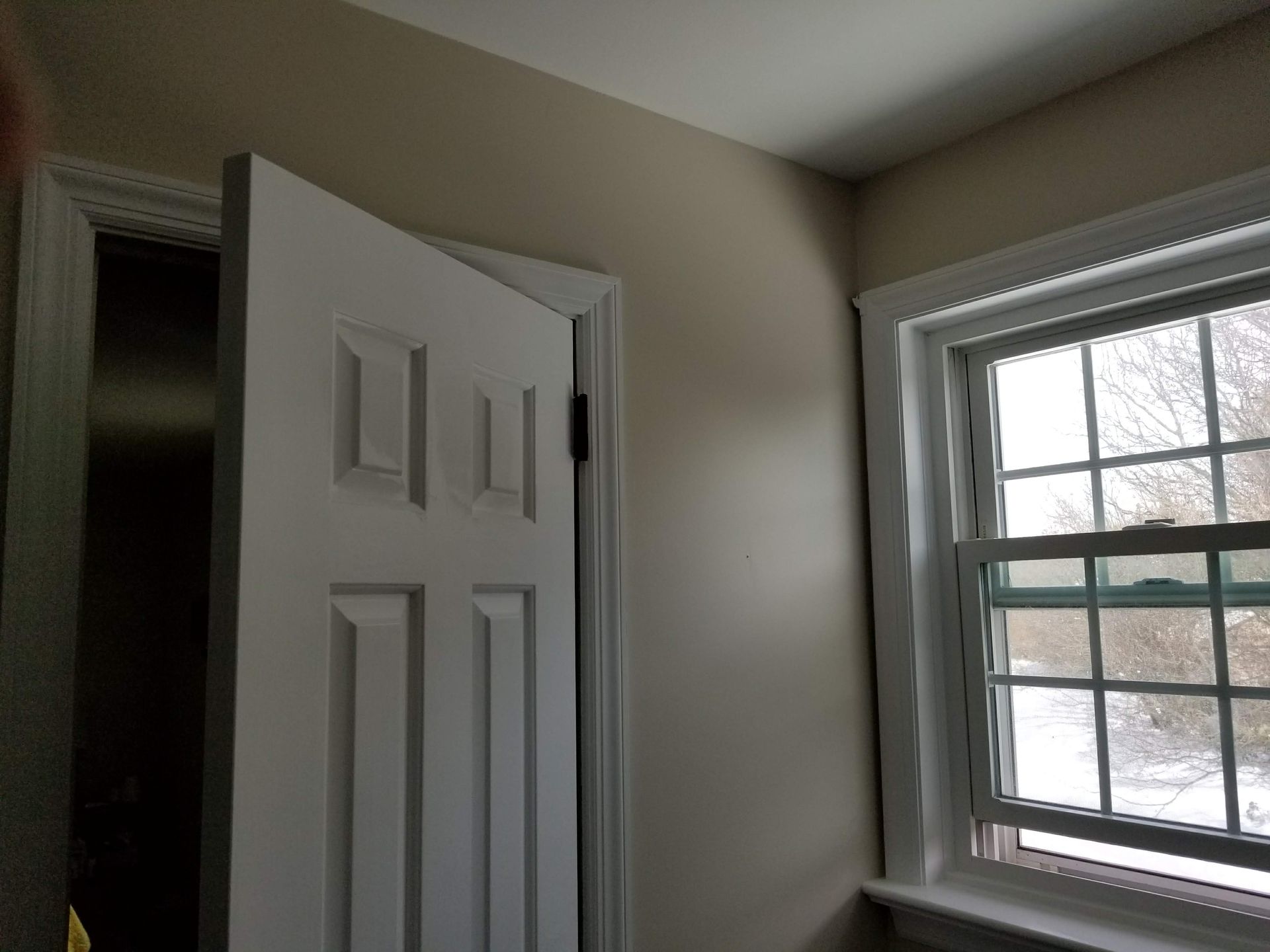 A white door is open in a room with two windows.