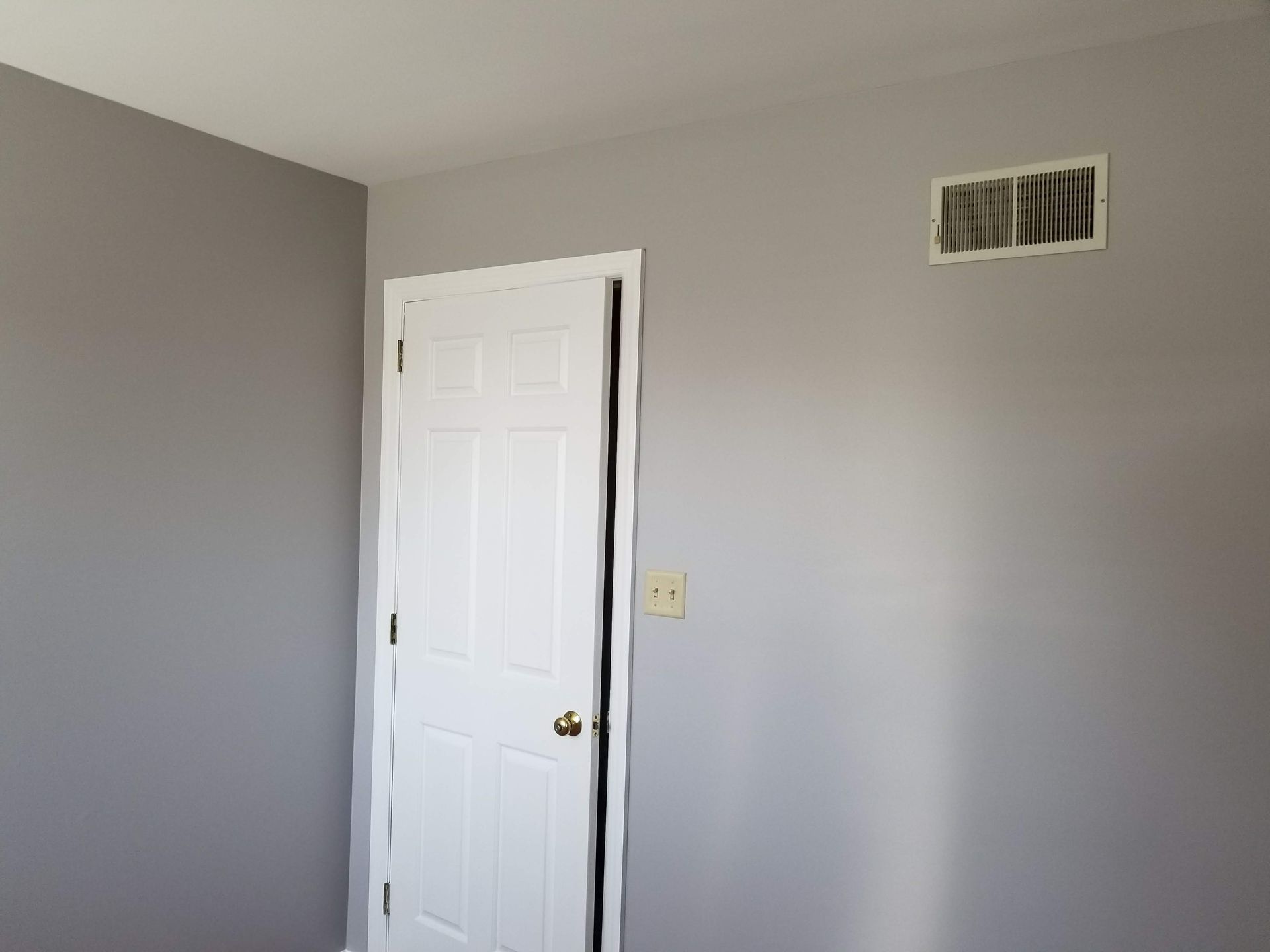 A bedroom with gray walls and a white door.