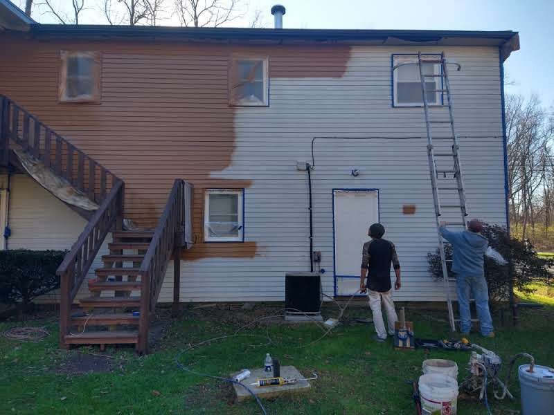 A couple of people are painting the side of a house.