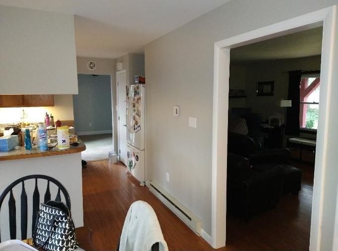 A kitchen with a refrigerator and a chair in it