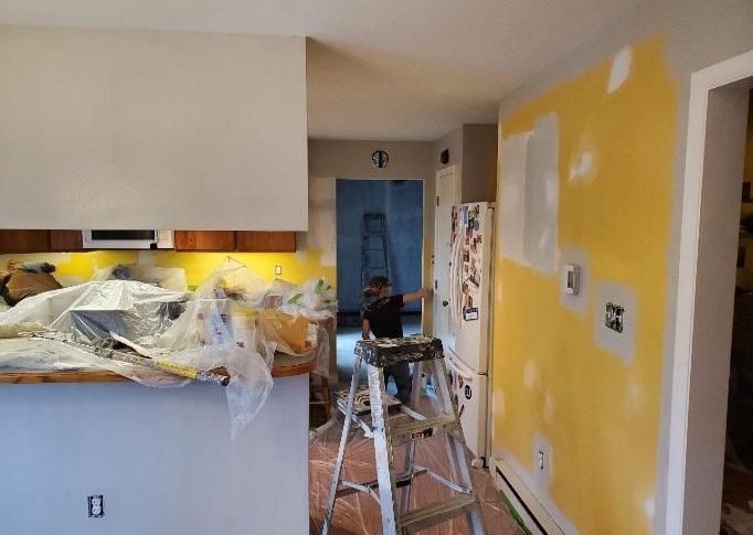 A man is sitting on a ladder in a kitchen.