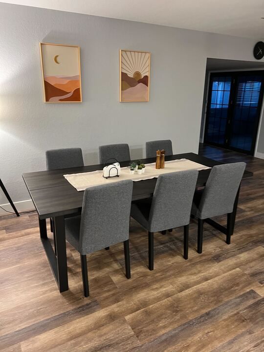 A dining room with a table and chairs and paintings on the wall.