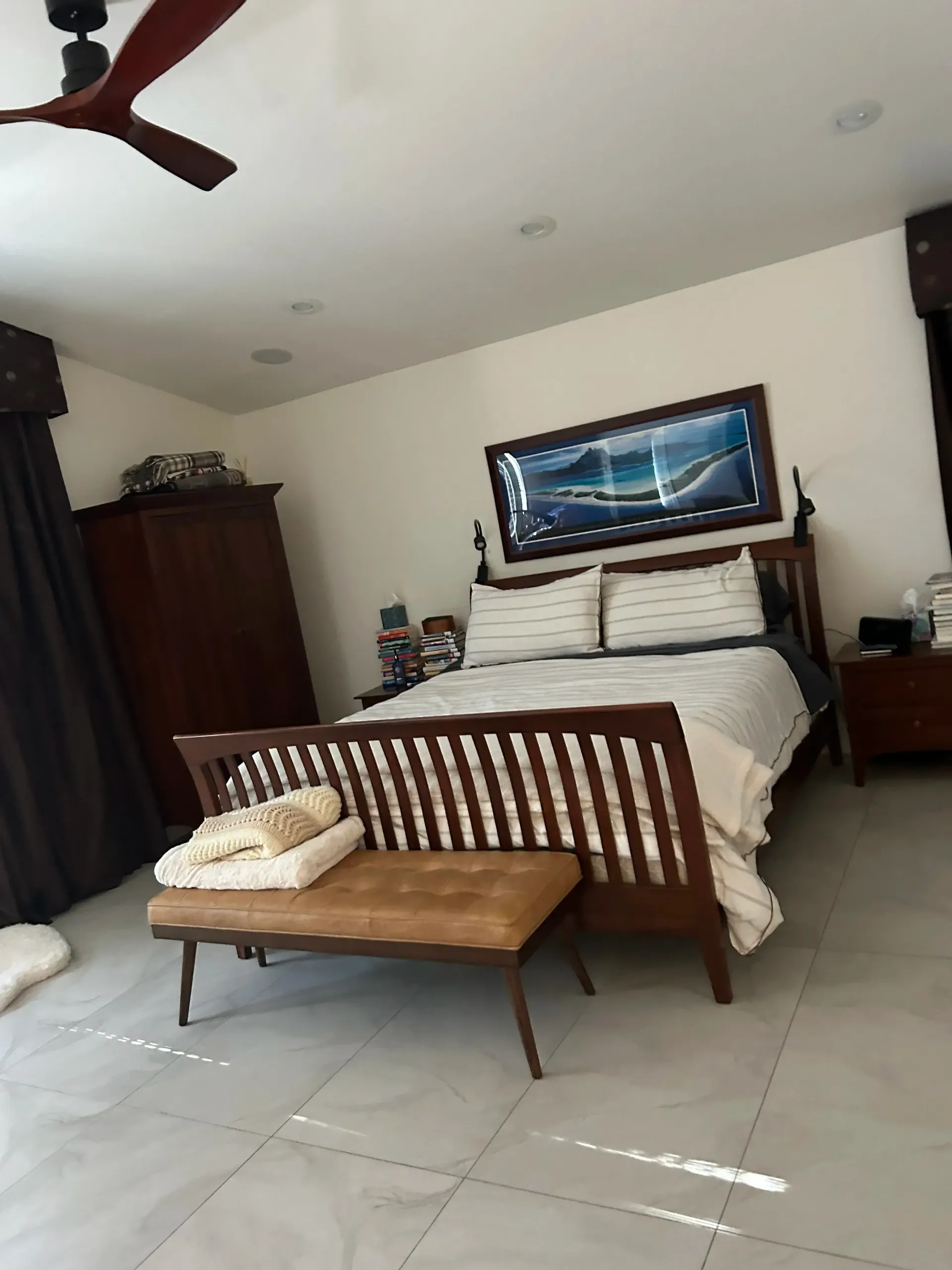 A bedroom with a large bed and a ceiling fan