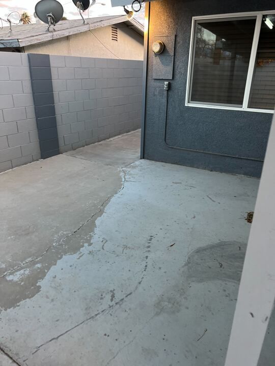 A patio with a window and a satellite dish on the roof of a house.