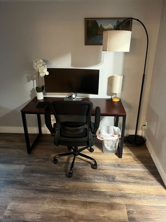 A desk with a chair and a computer on it in a room.