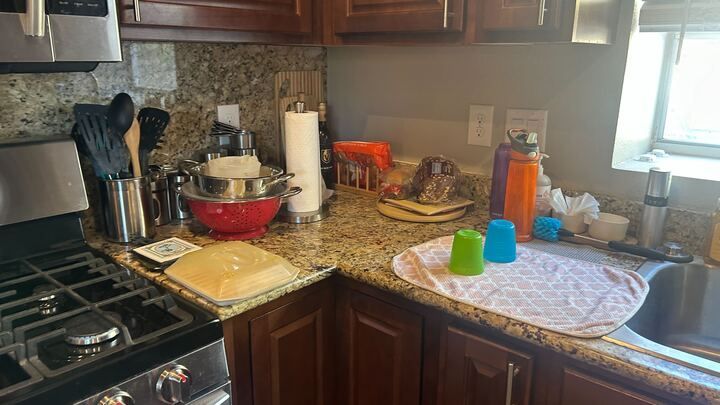 A kitchen with a stove , sink , and utensils on the counter.