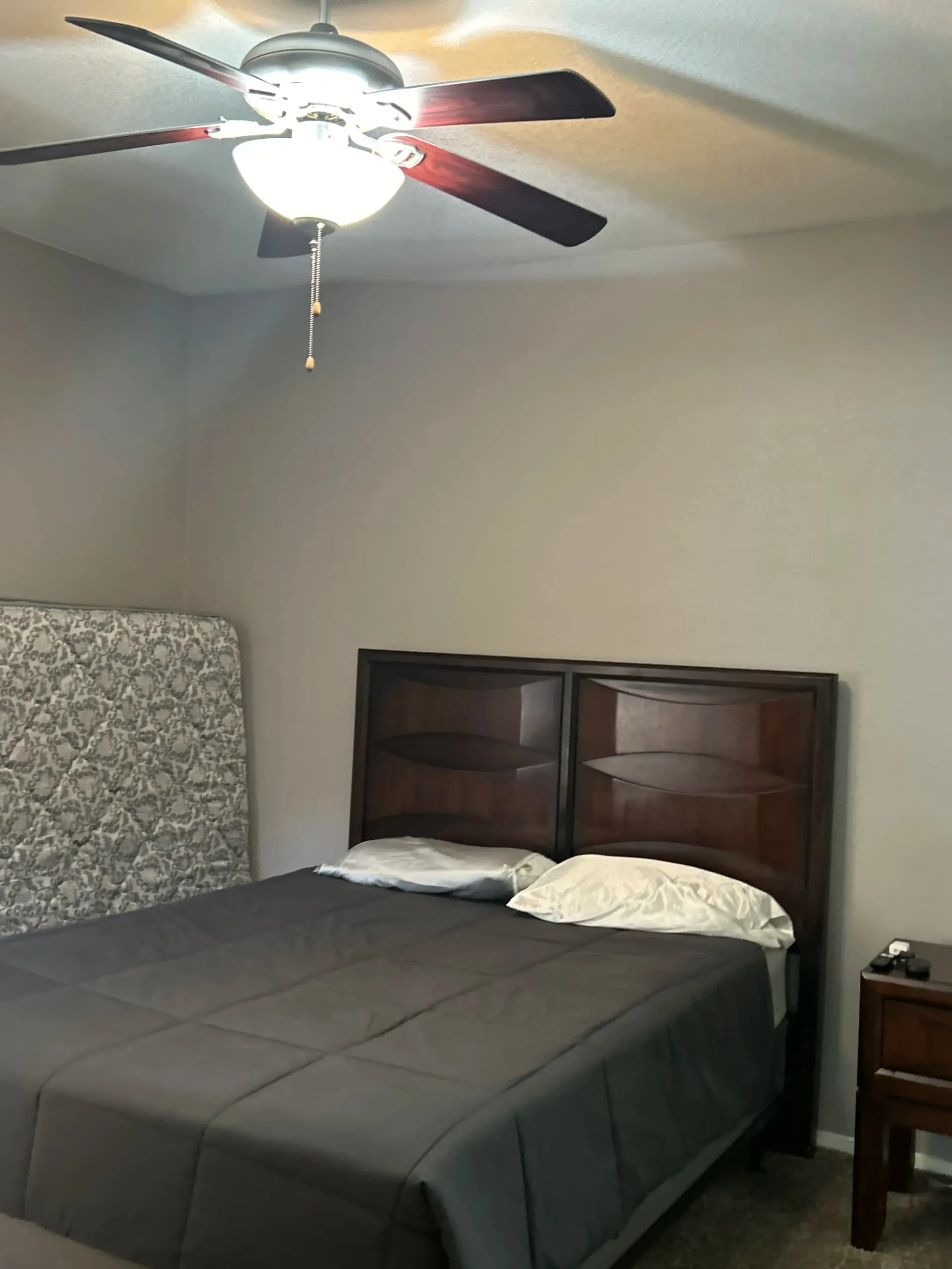 A bedroom with a bed and a ceiling fan