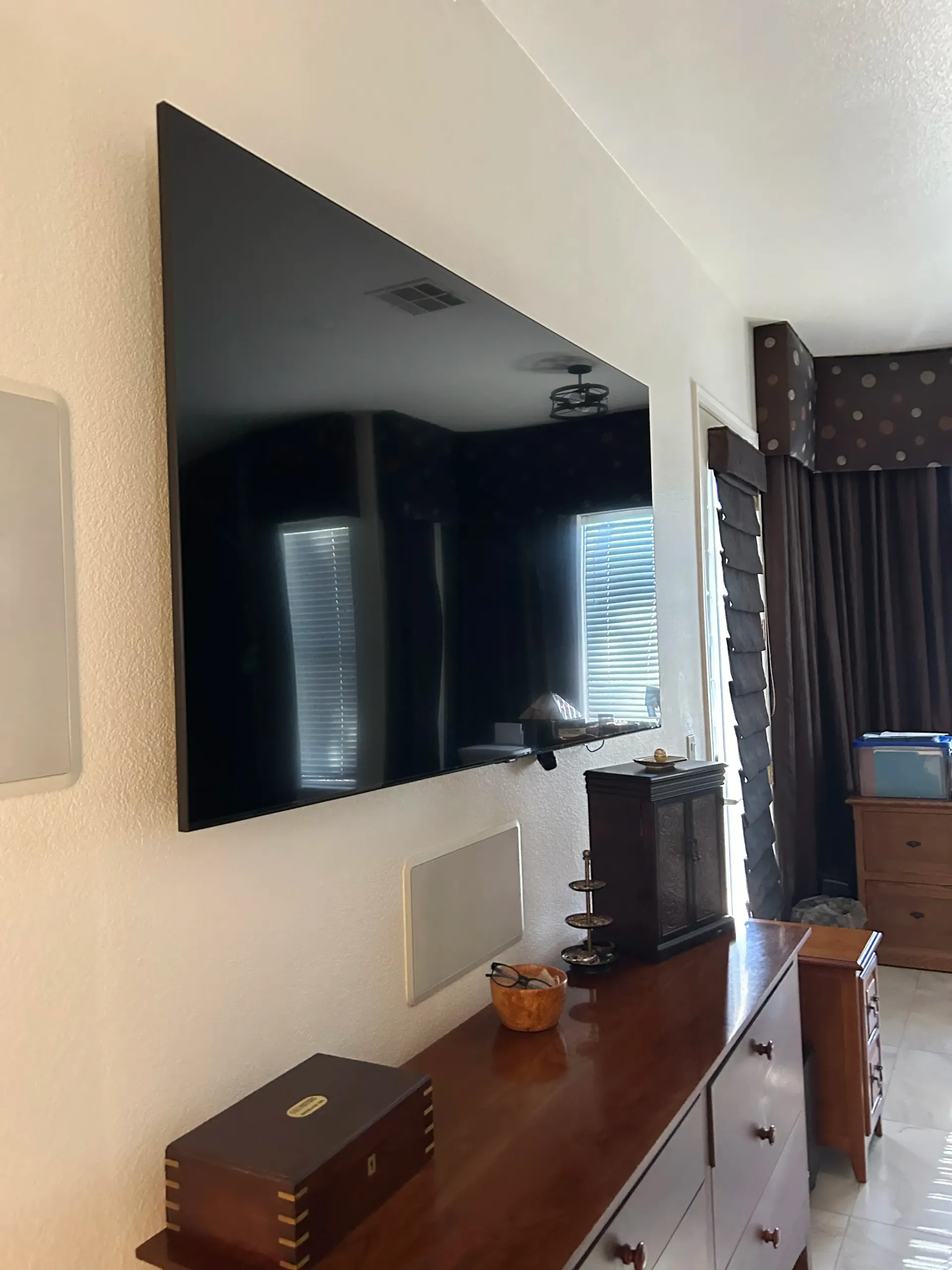 A large flat screen tv is mounted on a wall above a dresser