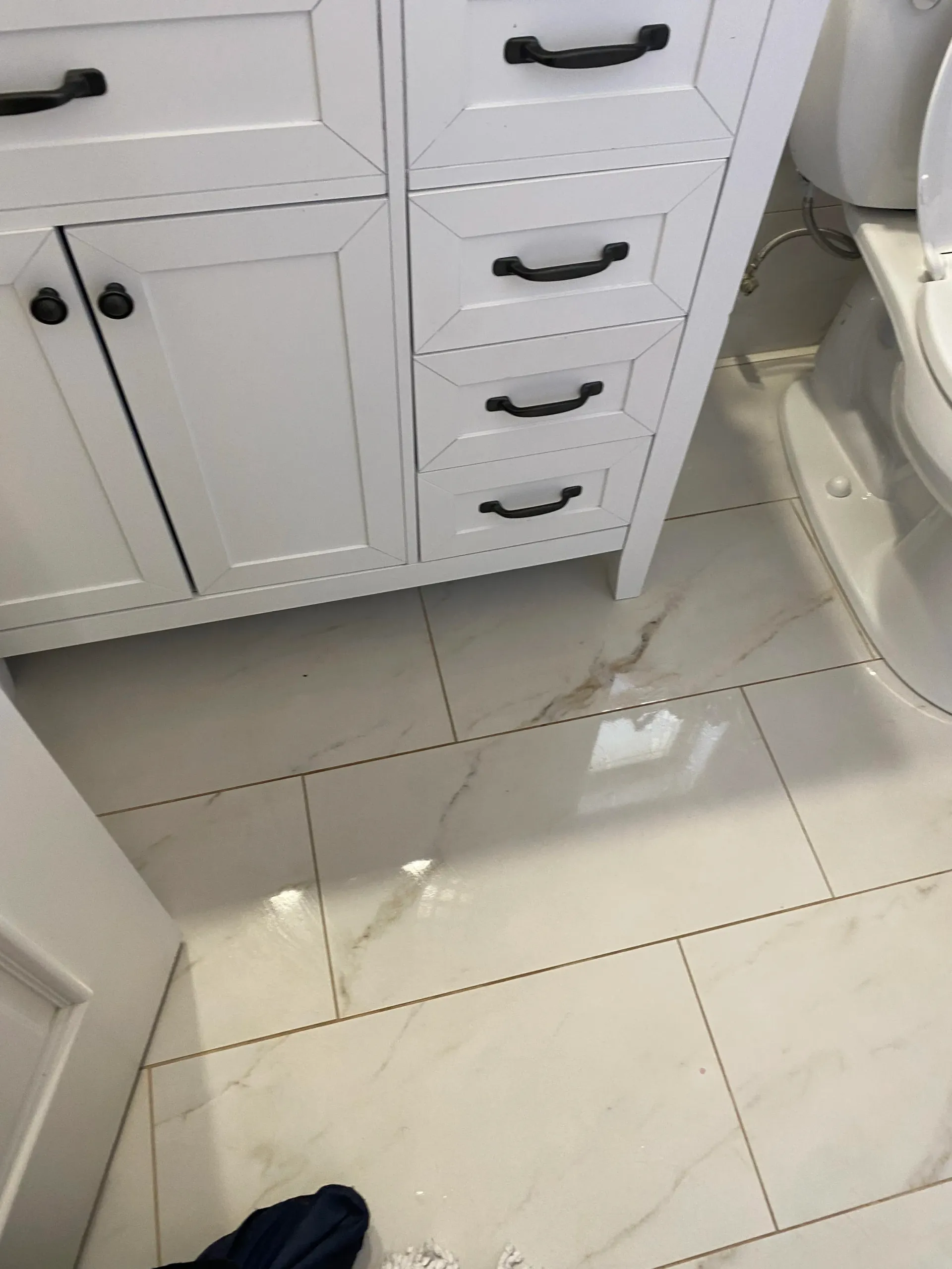 A bathroom with a white vanity , toilet , and tile floor.