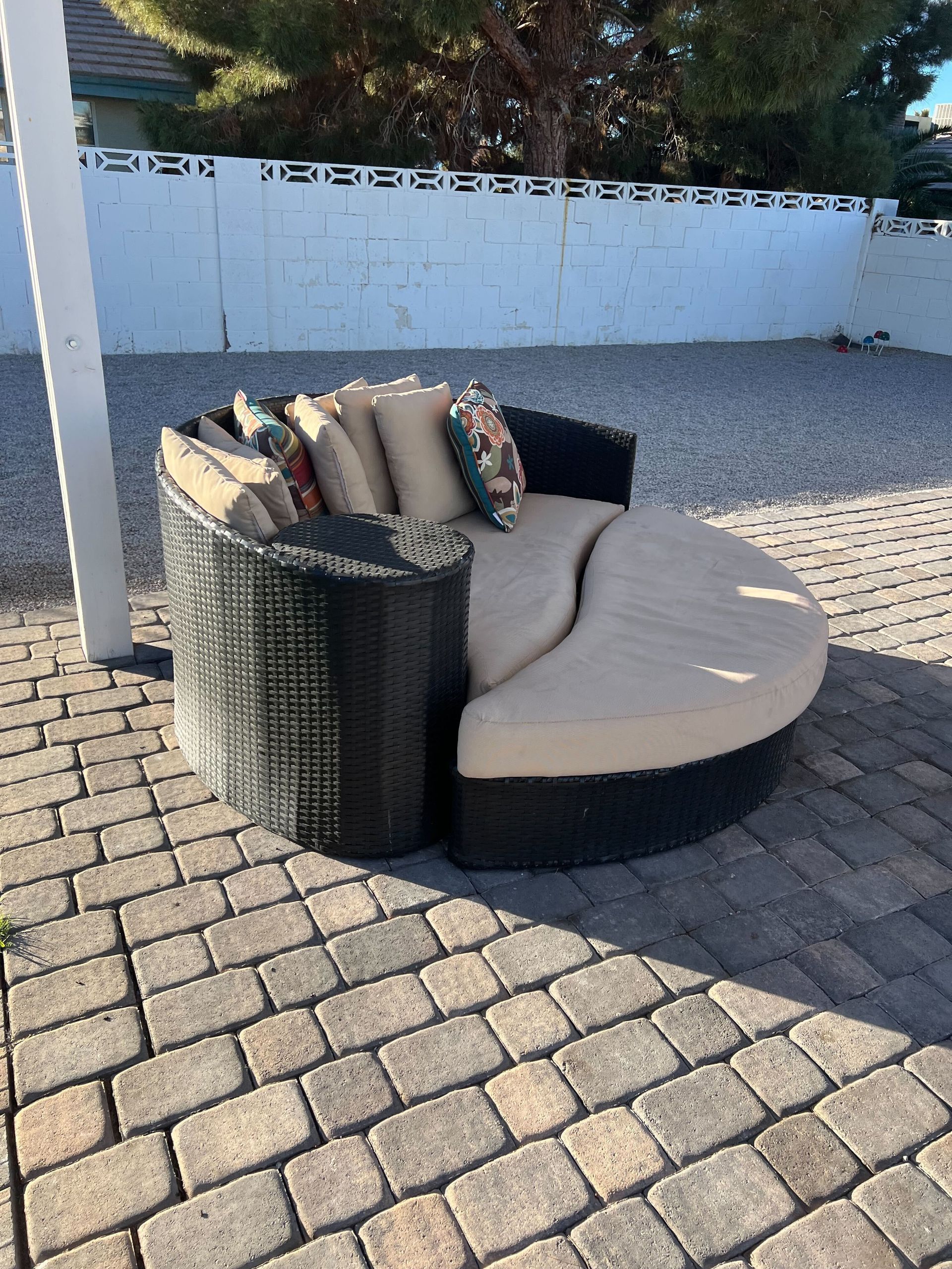 A round couch is sitting on a brick patio