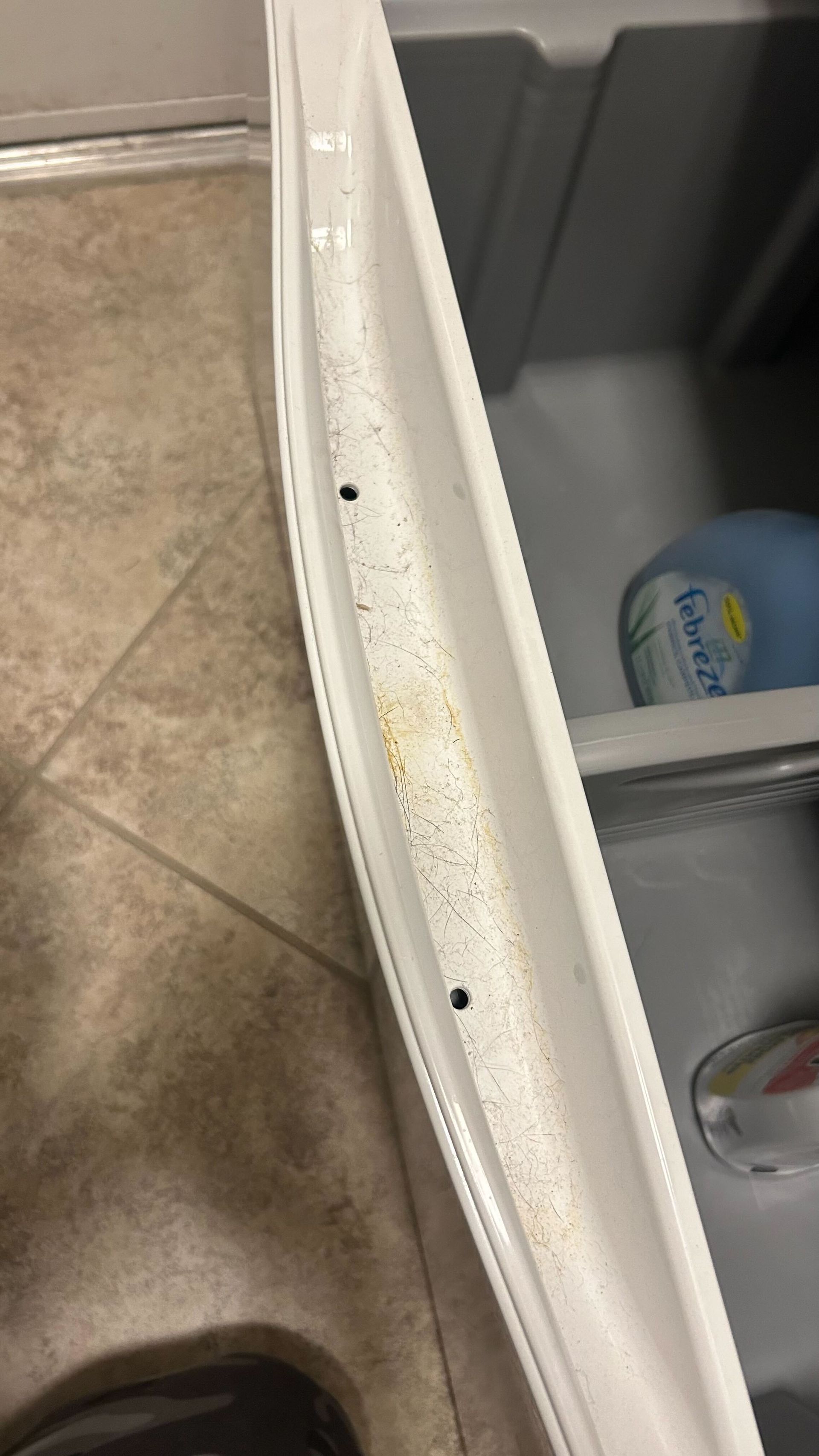 A close up of a dirty refrigerator door with a bottle of water in it.