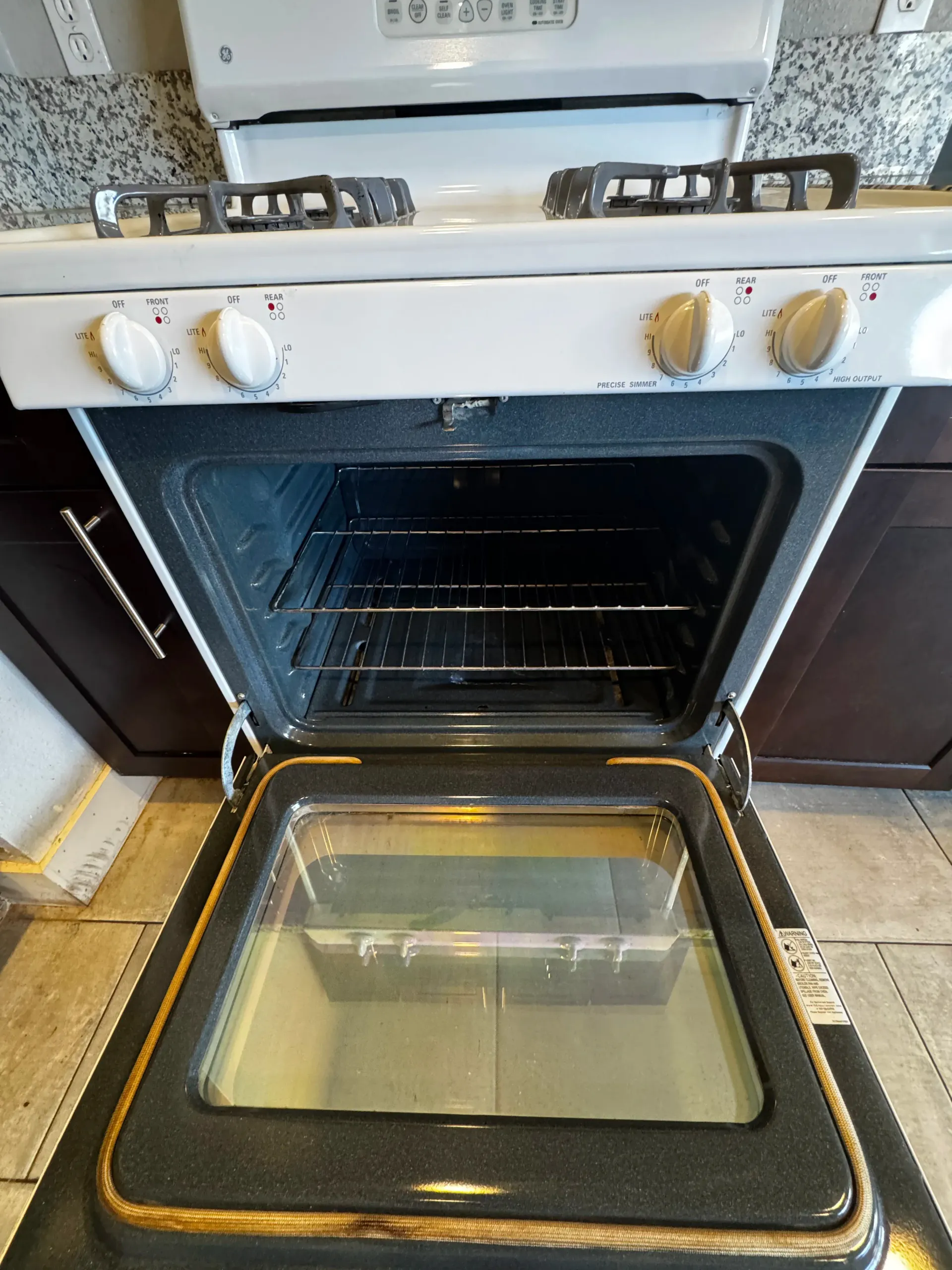 A white stove with the door open in a kitchen.