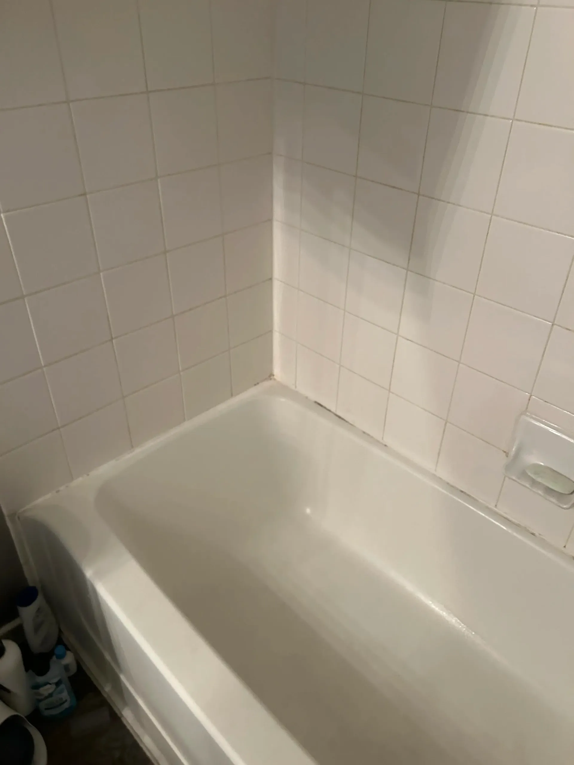 A white bathtub in a bathroom with white tiles.