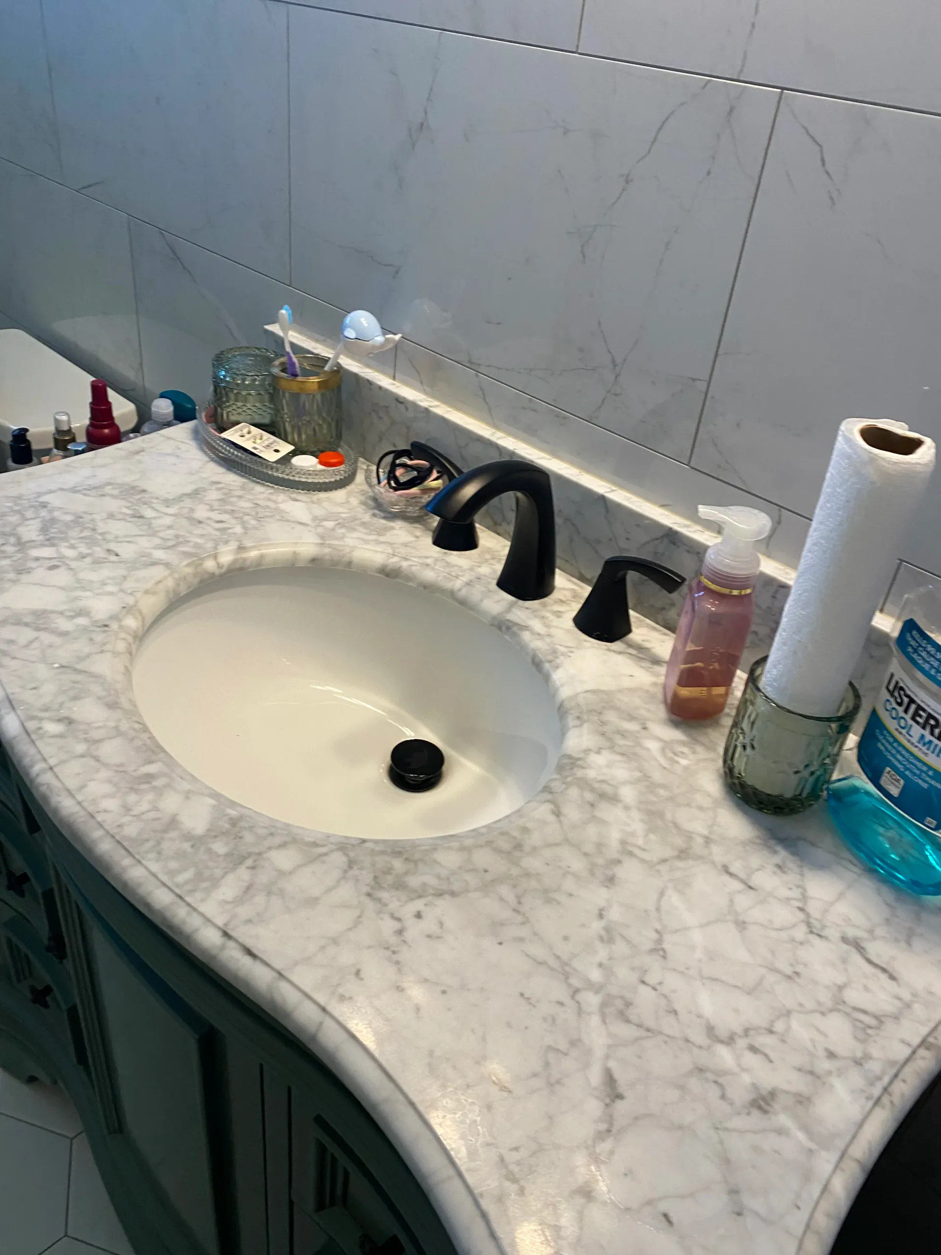 A bathroom sink with a marble counter top and a toilet.