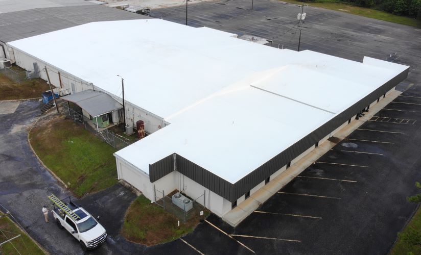 An aerial view of a large building with a white roof.