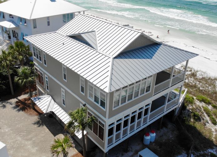 An aerial view of a house on stilts next to the ocean