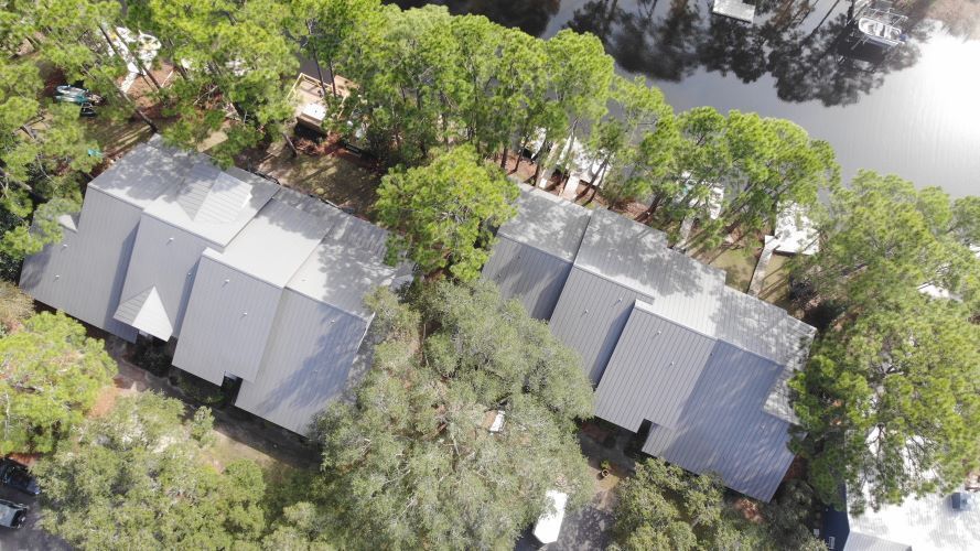 An aerial view of a row of houses surrounded by trees and a body of water.