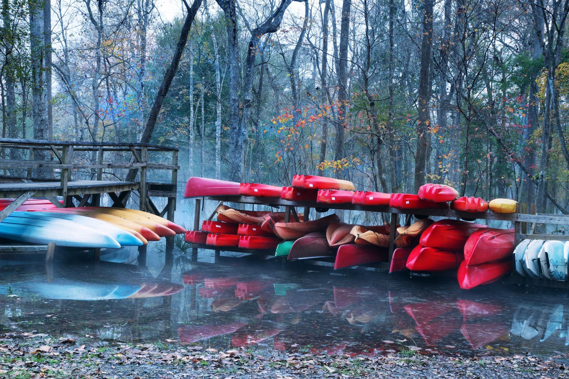 A bunch of kayaks are lined up on a dock in the water