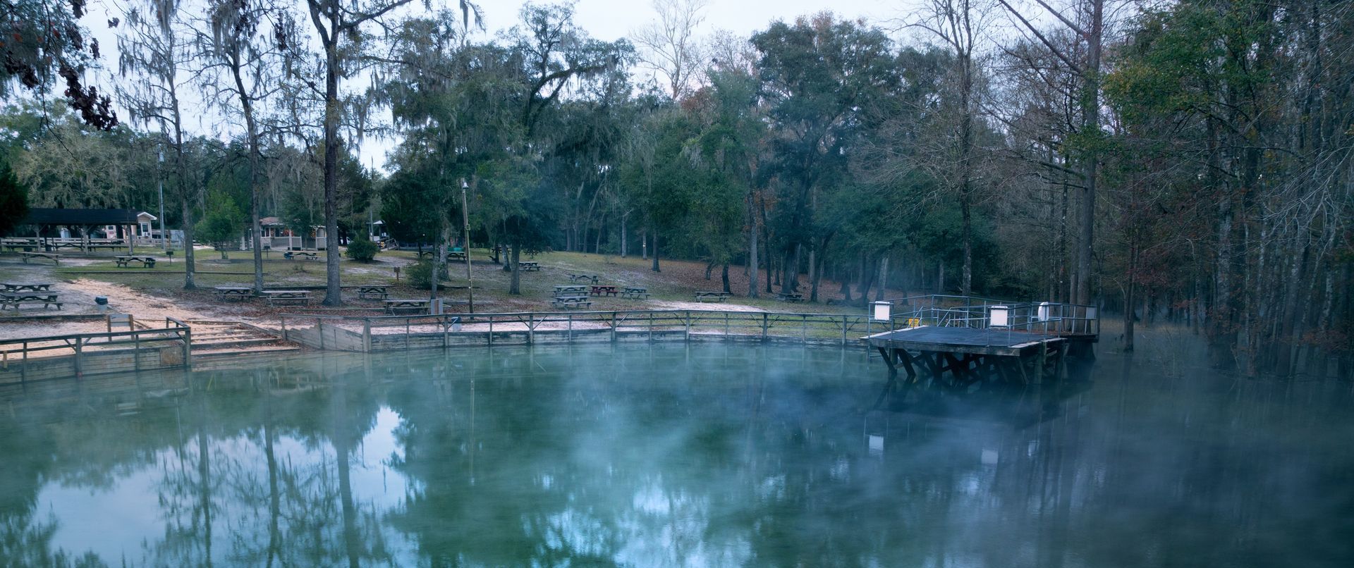 There is a dock in the middle of a lake surrounded by trees.