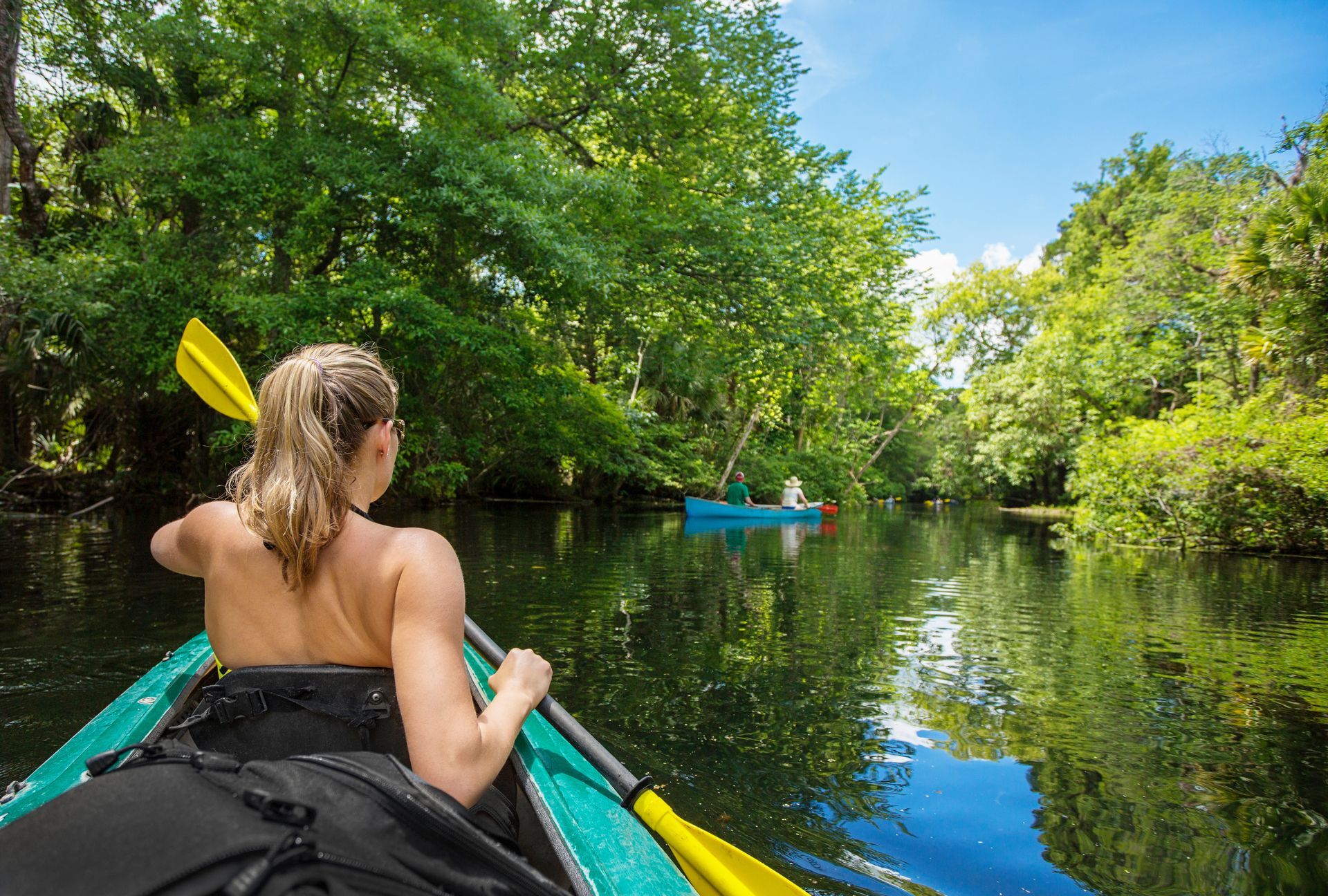 A woman is paddling a kayak down a river.