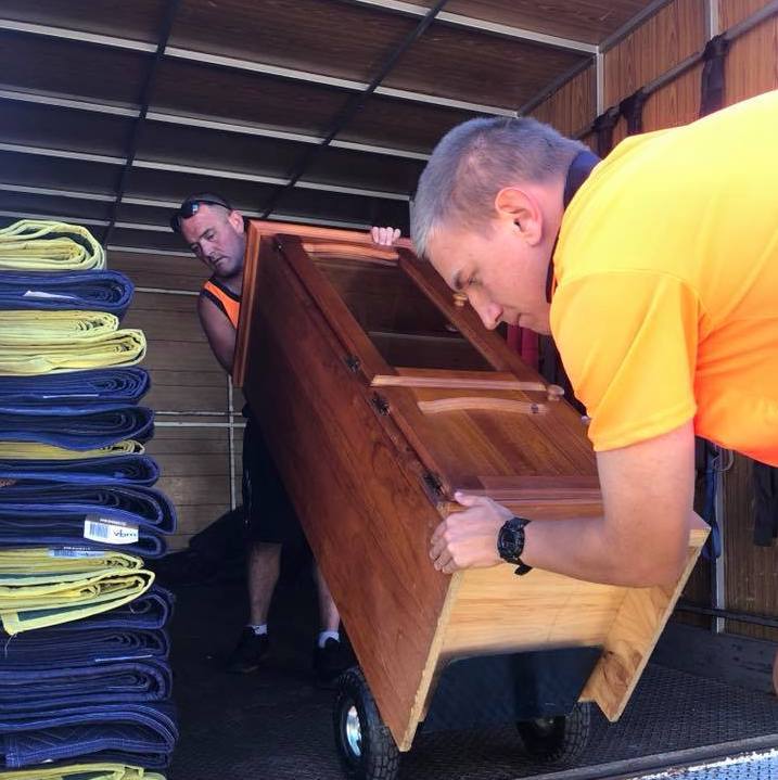 Removalists packing timber furniture into moving truck