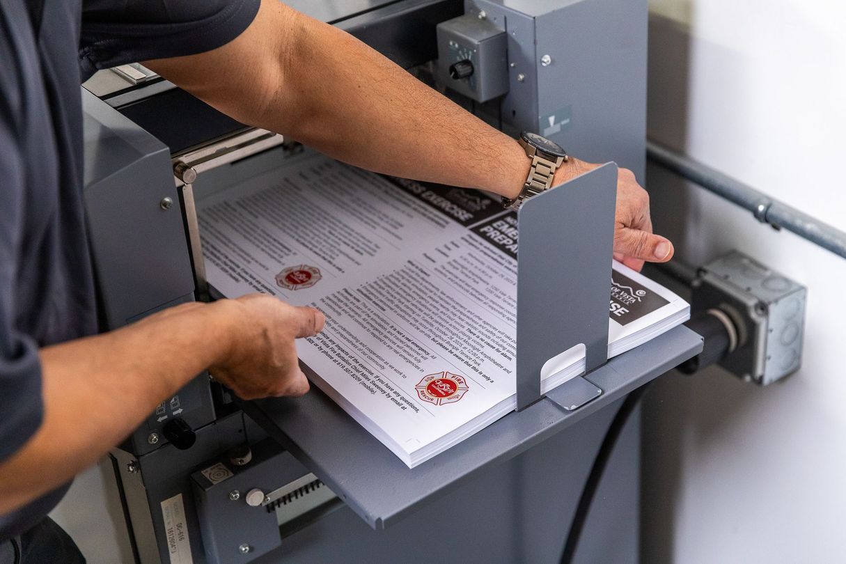 Person loading a stack of printed documents into a binding machine.