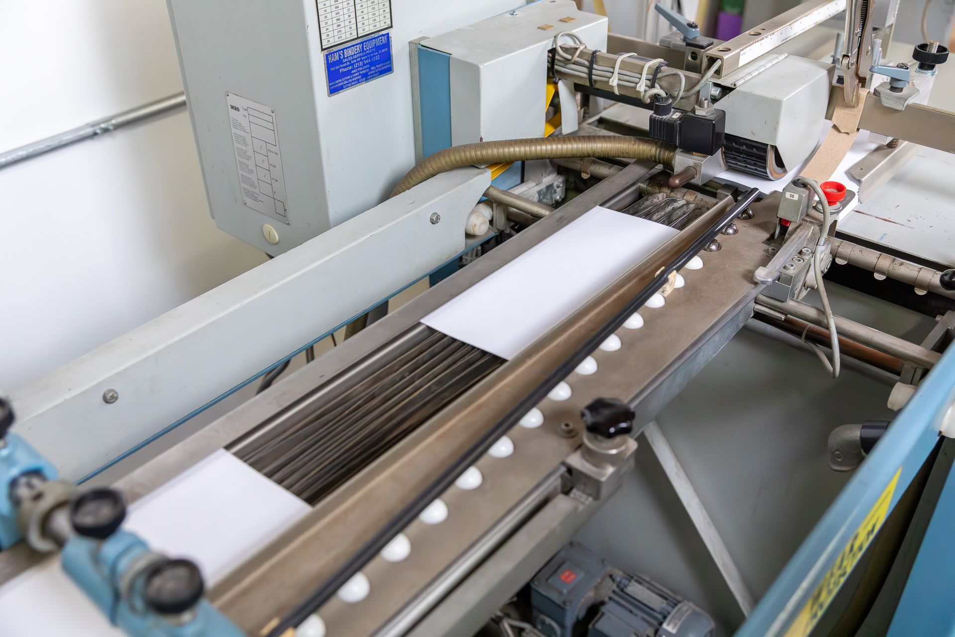 Production line with white rectangular items moving along a conveyor belt.