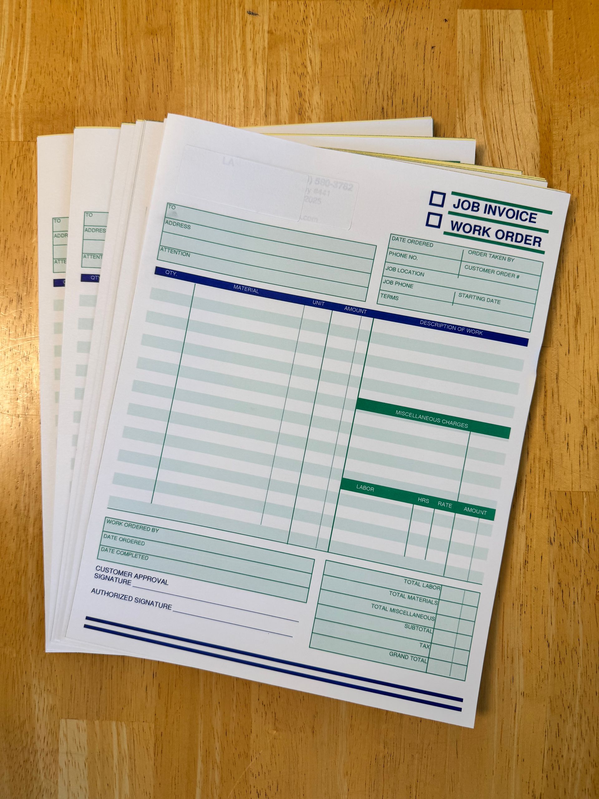 Stack of printed forms with green and blue lines on a wooden surface.