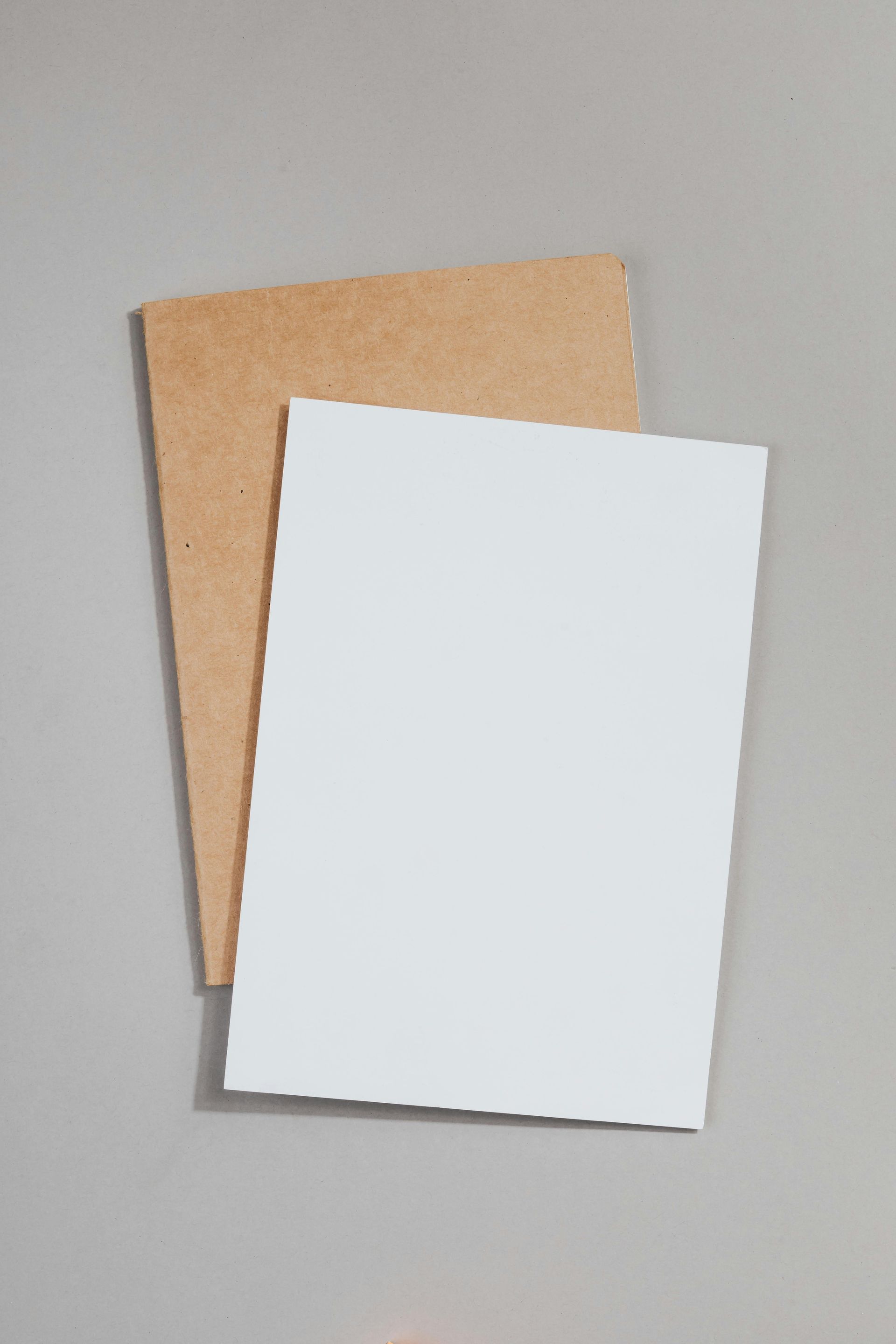 White blank card on top of a brown card, both on a gray surface.