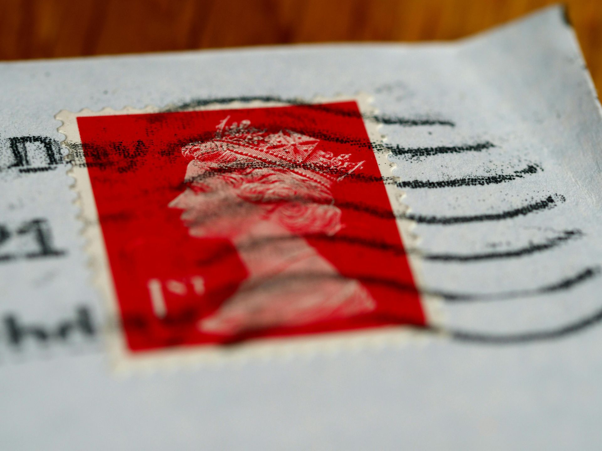 Red postage stamp on an envelope, featuring a profile of Queen Elizabeth II.
