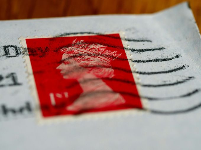 Red postage stamp on an envelope, featuring a profile of Queen Elizabeth II.