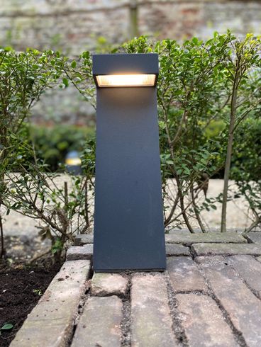 Een zwarte paal met een licht erop staat op een stenen loopbrug.