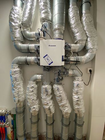 Een stel buizen zijn verbonden met een doos aan de muur.