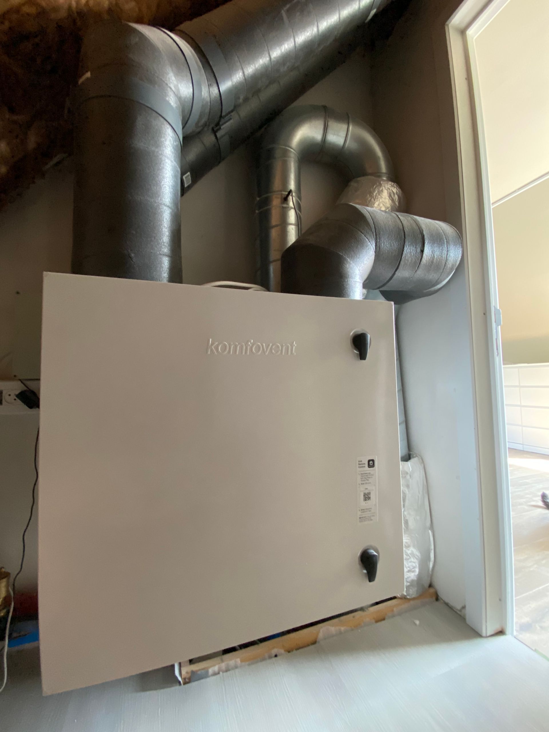 In een ruimte naast een deur wordt een ventilatiesysteem geïnstalleerd.