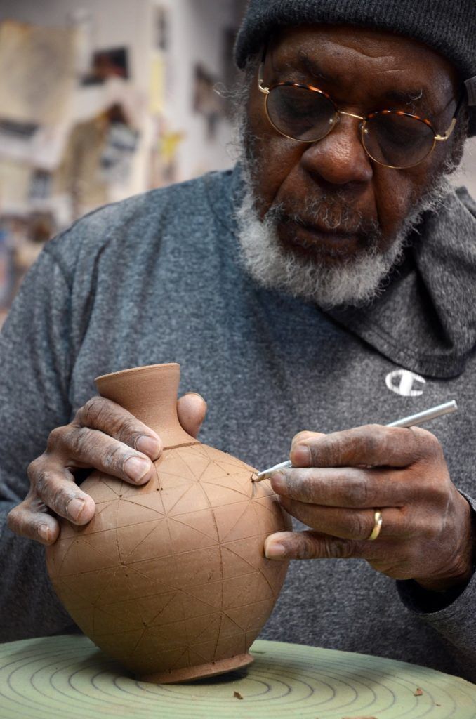 David MacDonald carves lines into a clay pot