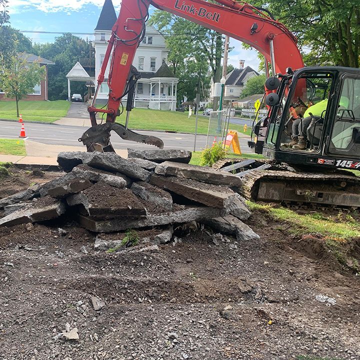 An excavator piles up sections of concrete removed from the front of the Schweinffurth Art Center