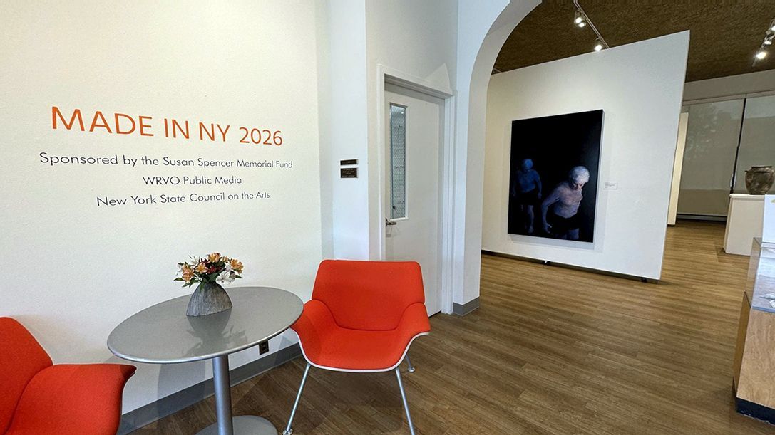 An opening shot of an exhibit with the title Made in NY 2026, a dark blue painting with two figures can be seen in the background