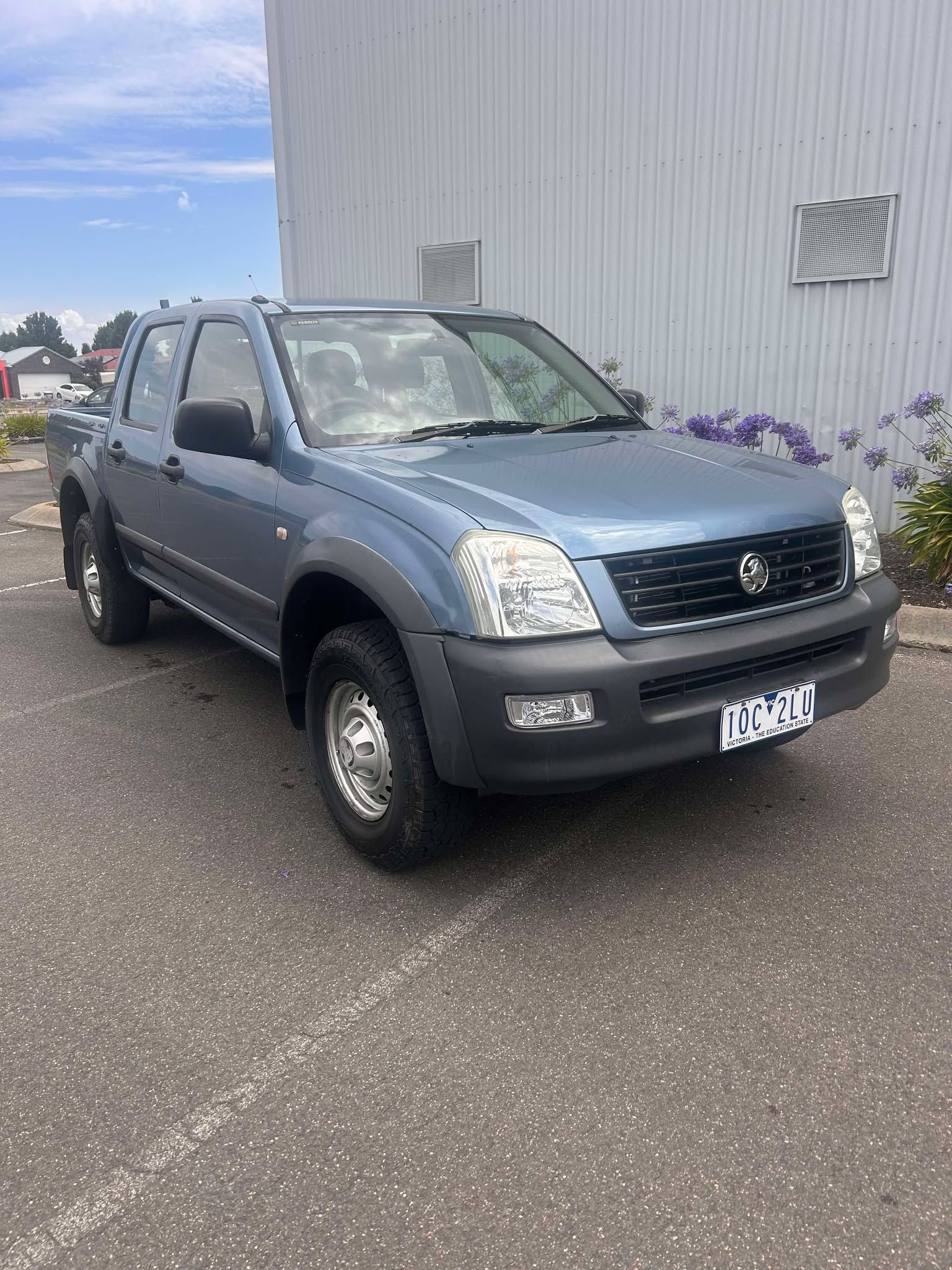 A blue truck is parked in a parking lot in front of a building.