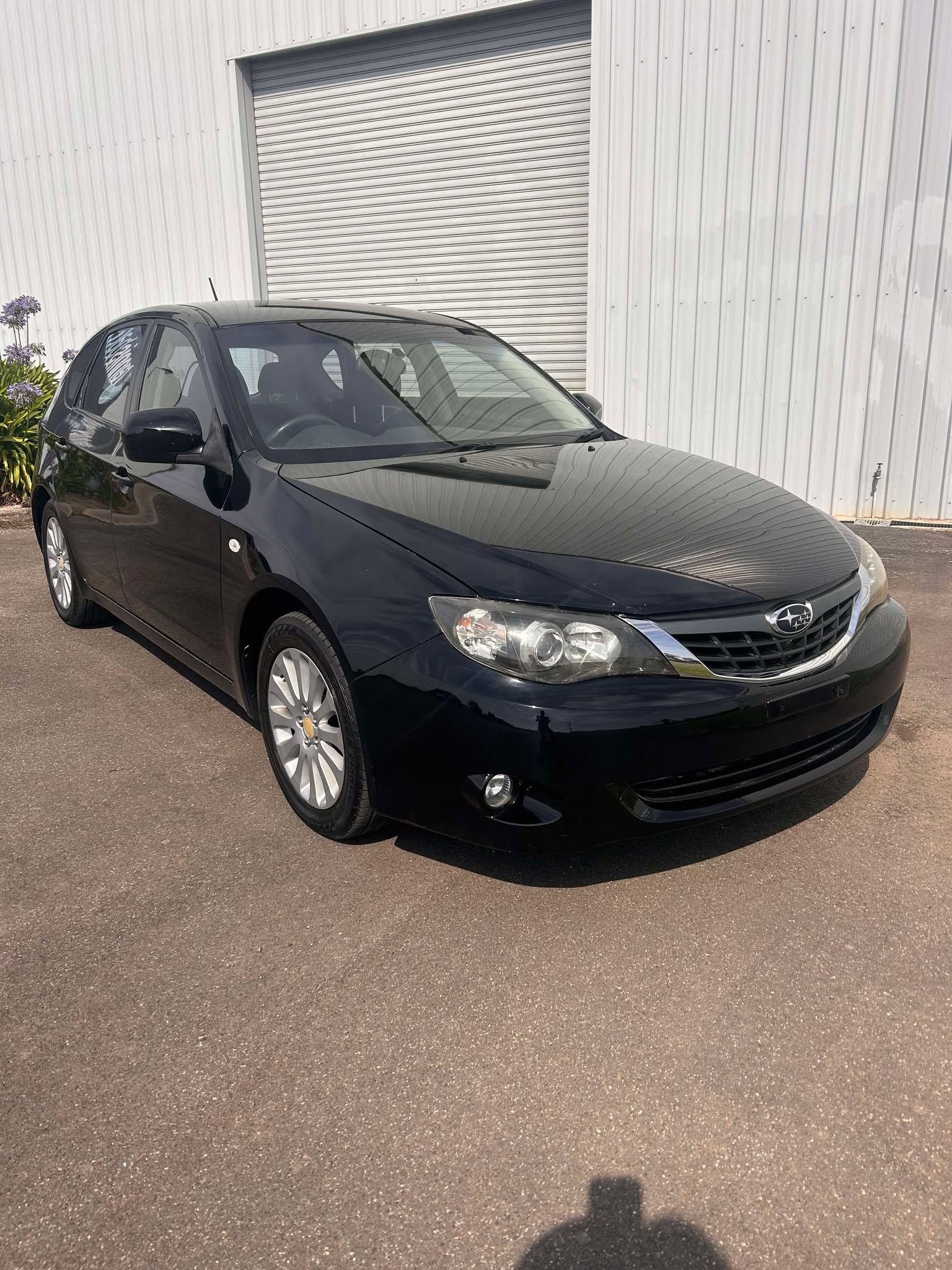 A black car is parked in front of a white building.