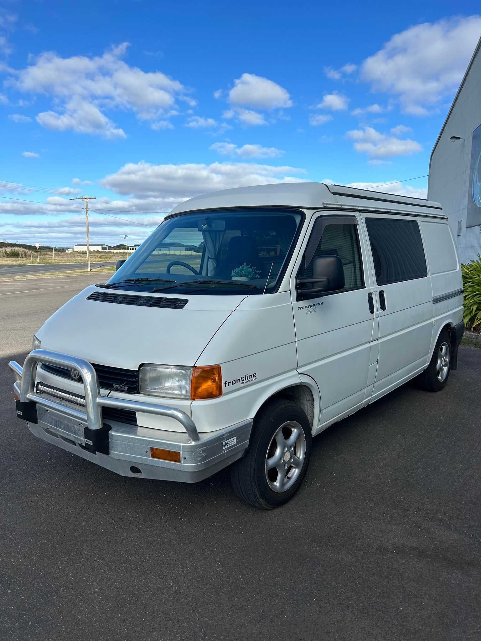 A white van is parked in a parking lot in front of a building.