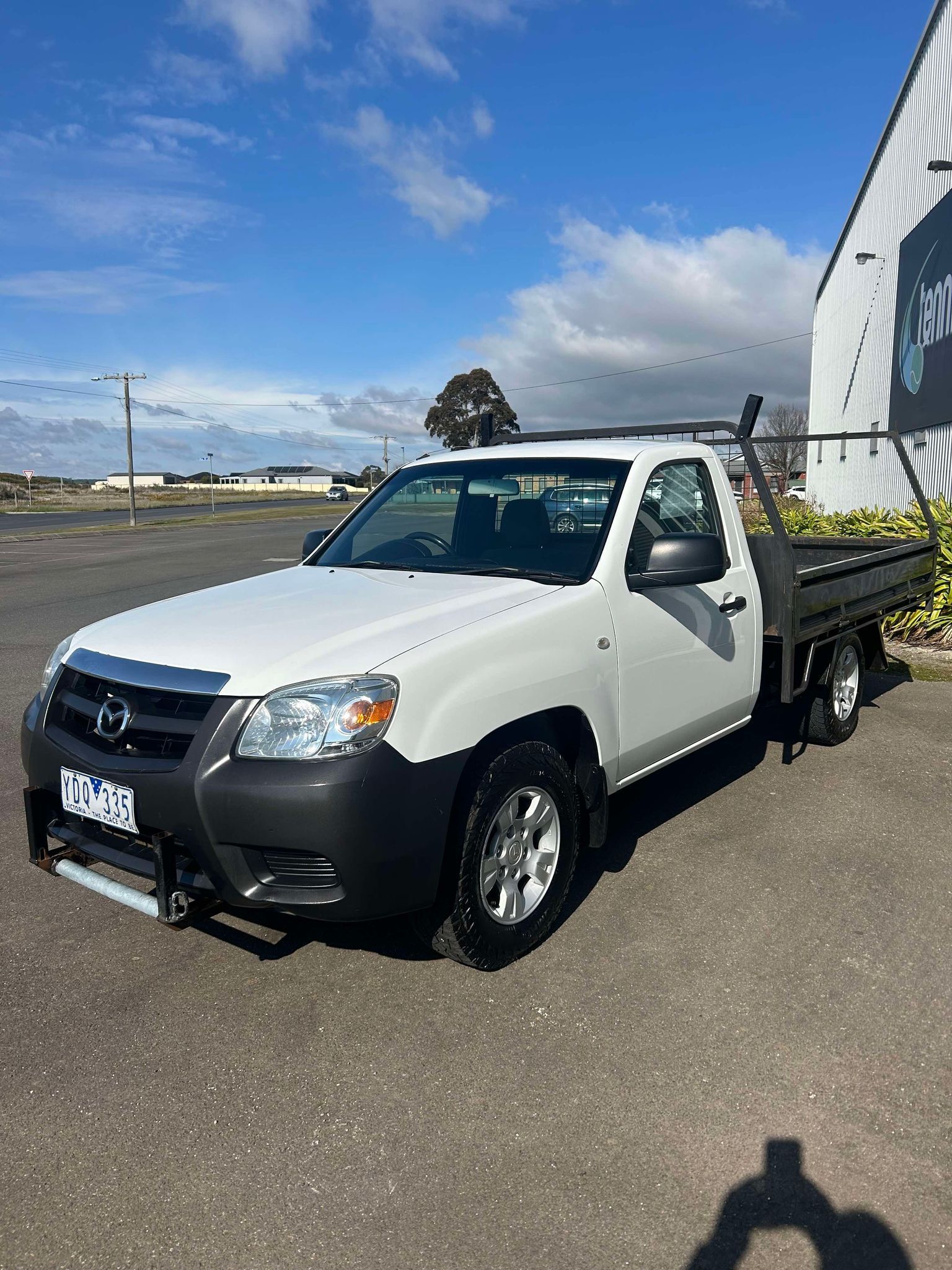 A white truck is parked in a parking lot in front of a building.