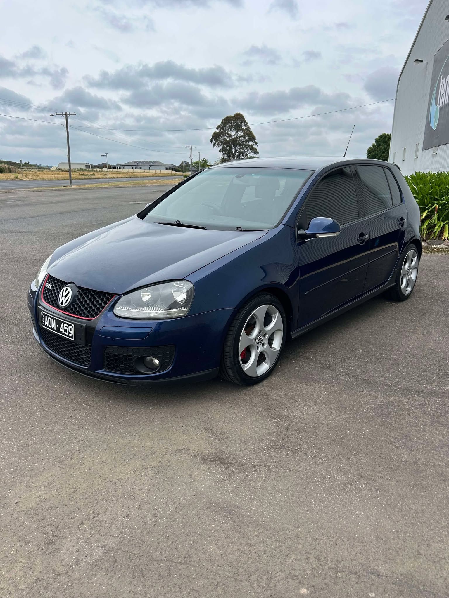 A blue volkswagen golf is parked in a parking lot.