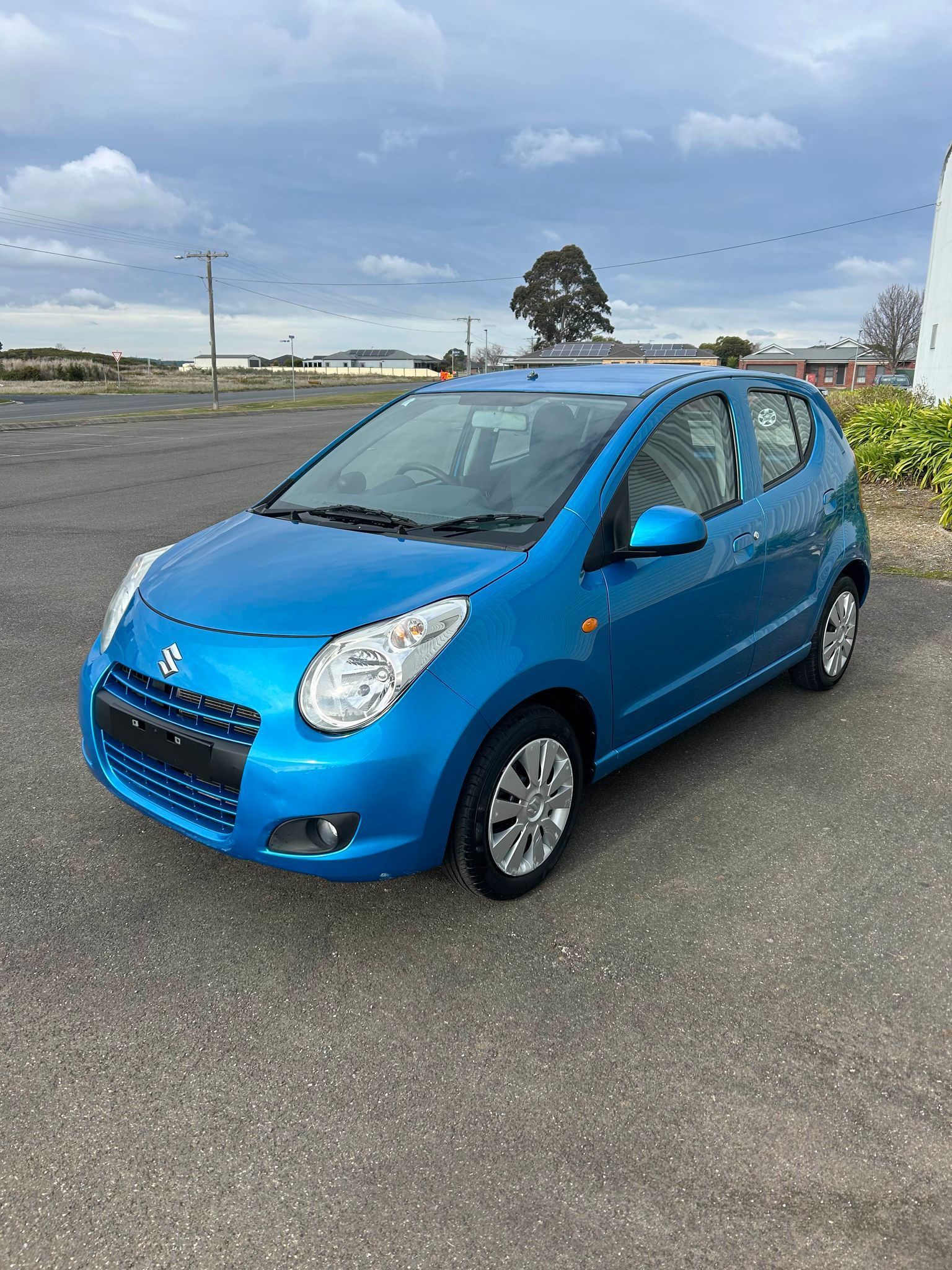 A blue car is parked in a parking lot.