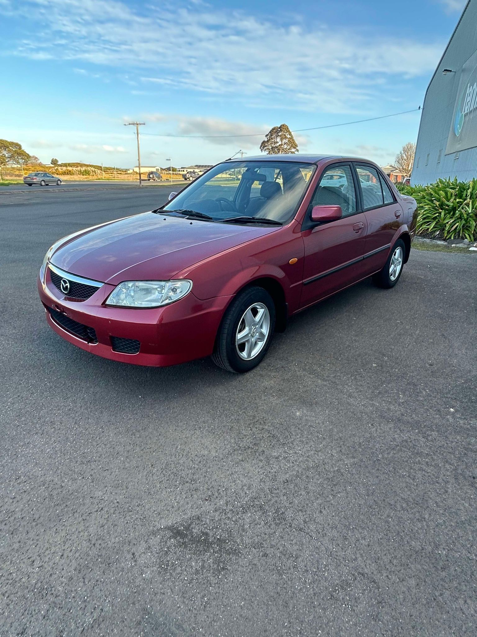 A red mazda 3 is parked in a parking lot.